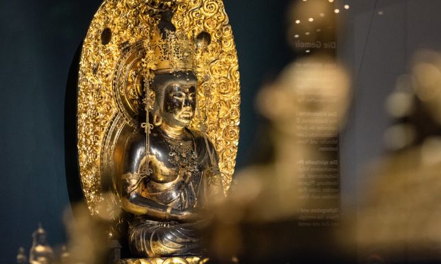 Buddha in gold and black at the back of the picture behind further buddha figures which are blurred